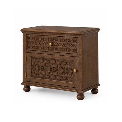 Angled view of Winnetka carved mango wood nightstand with brass knobs and turned bun feet