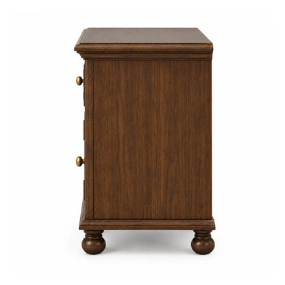 Side profile of Winnetka solid wood bedside table showing molded top and bun feet